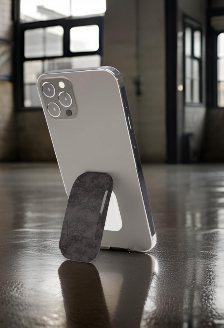 Icon featuring a phone resting on a glossy floor, showcasing a vintage-designed phone grip in dark floral design